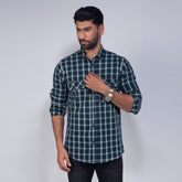 Man wearing a green and gray plaid shirt against a plain background