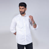 Man wearing a white shirt with rolled-up sleeves on a plain background