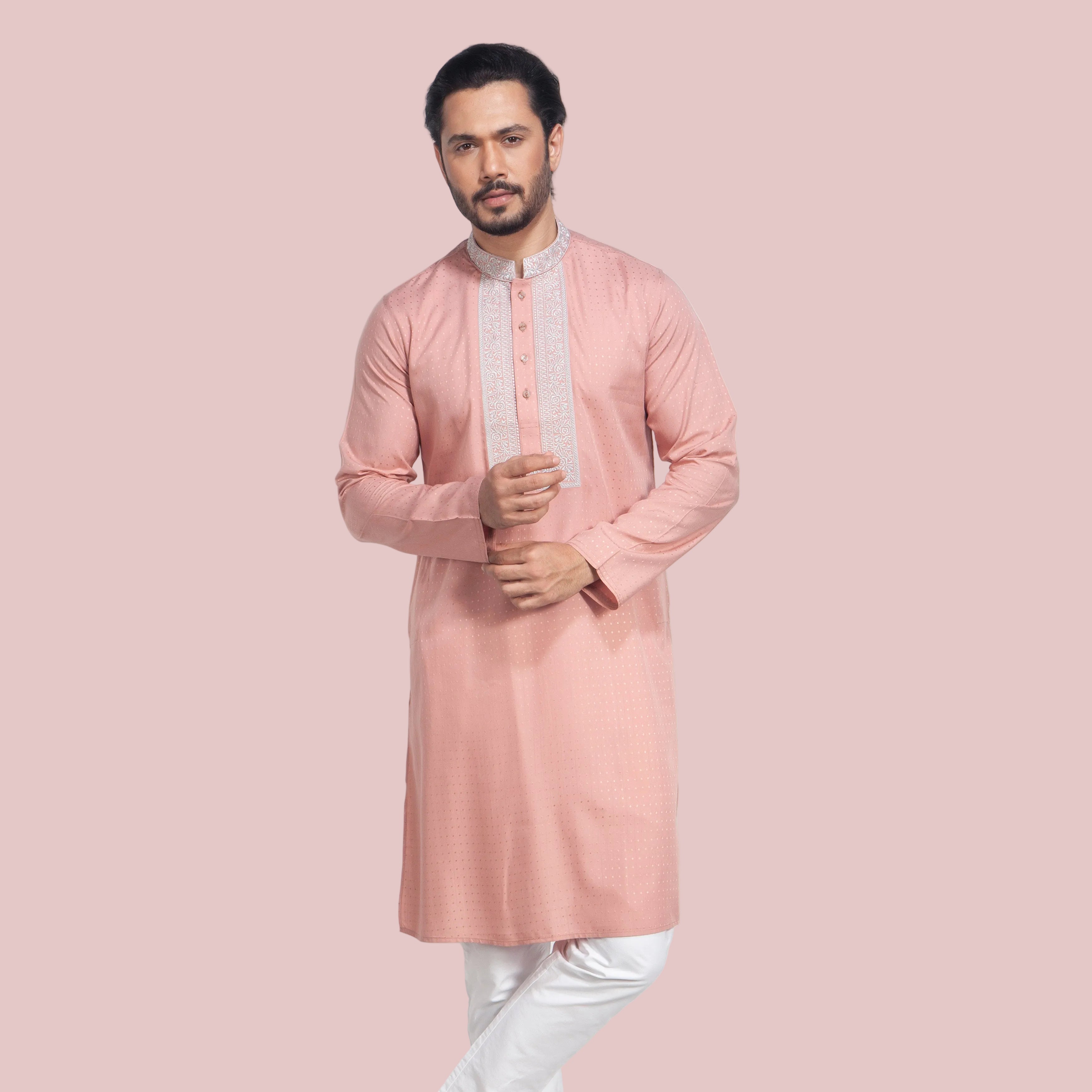Man wearing a pink panjabi with white pants on a light gray background