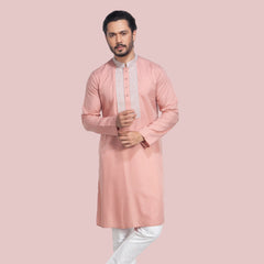 Man wearing a pink panjabi with white pants on a light gray background