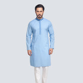 Man wearing a light blue panjabi with white pants on a plain background