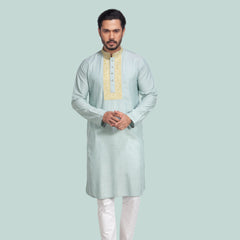 Man wearing a light green panjabi with white pants on a plain background