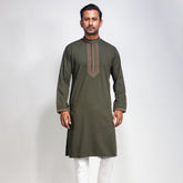 Man wearing an olive green panjabi with white pants on a light gray background