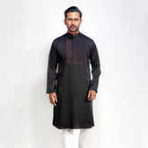 Man wearing a black panjbai with white pants on a white background