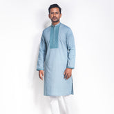 Man wearing a light blue panjabi with white pants on a white background