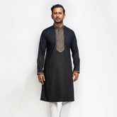 Man wearing a black embroidered panjabi against a white background
