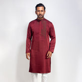 Man wearing a maroon kurta with white pants on a light gray background
