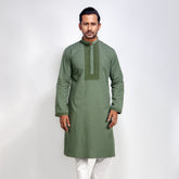 Man wearing a green kurta with white pants on a light gray background