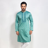 Man wearing a teal kurta with white pants on a light gray background