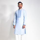 Man wearing a light blue panjabi with white pants on a plain background