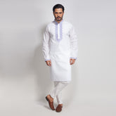 Man wearing a white kurta with embroidery on a light gray background