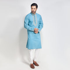 Man wearing a light blue kurta with white pants on a white background