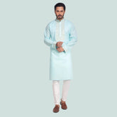 Man wearing a light blue kurta with white pants on a white background