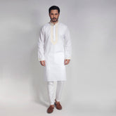 Man wearing a white kurta with embroidery on a plain background