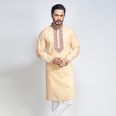 Man wearing a beige kurta with white pants on a light gray background