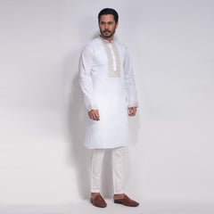 Man wearing a white kurta with embroidery on a plain background