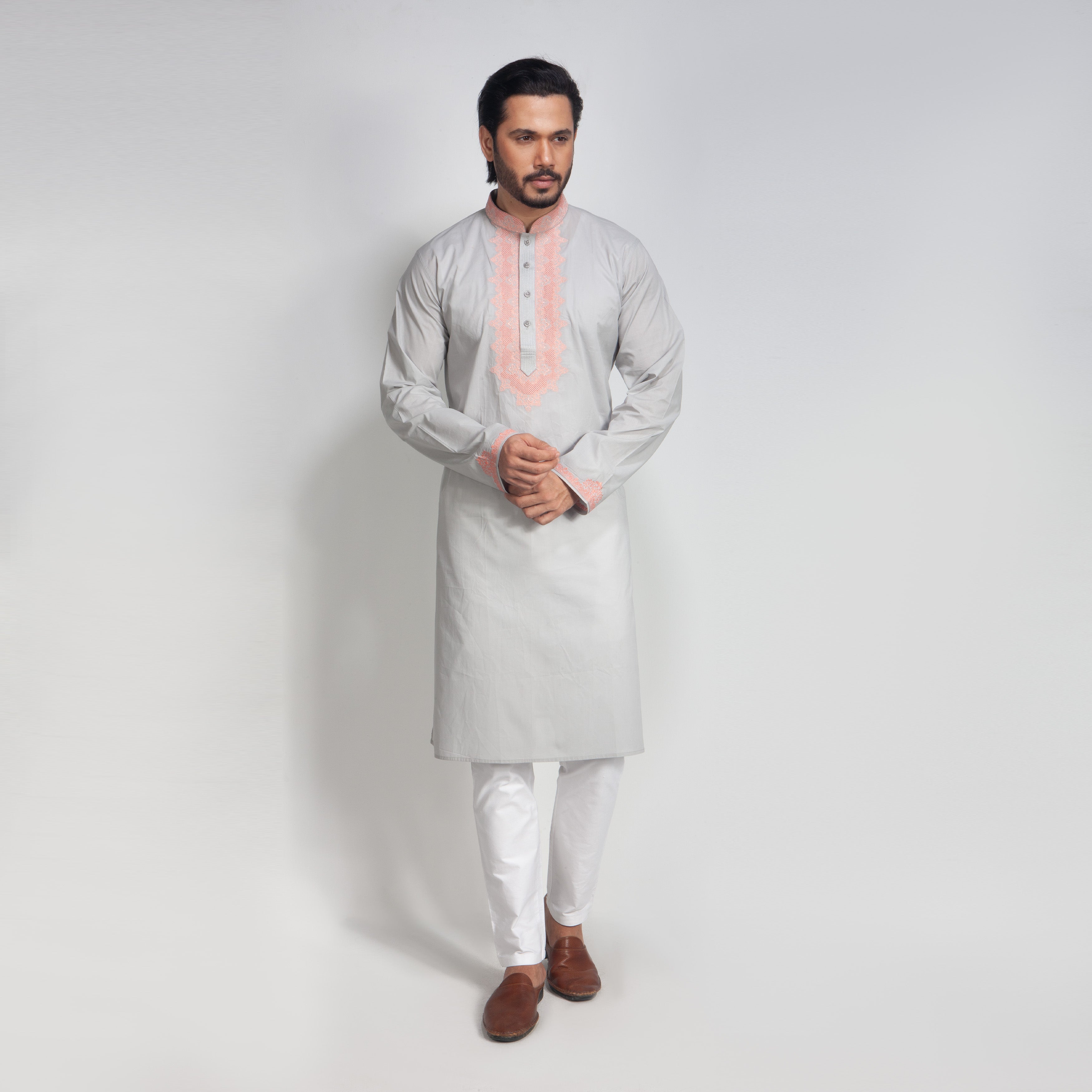 Man wearing a light gray kurta with white pants on a plain background