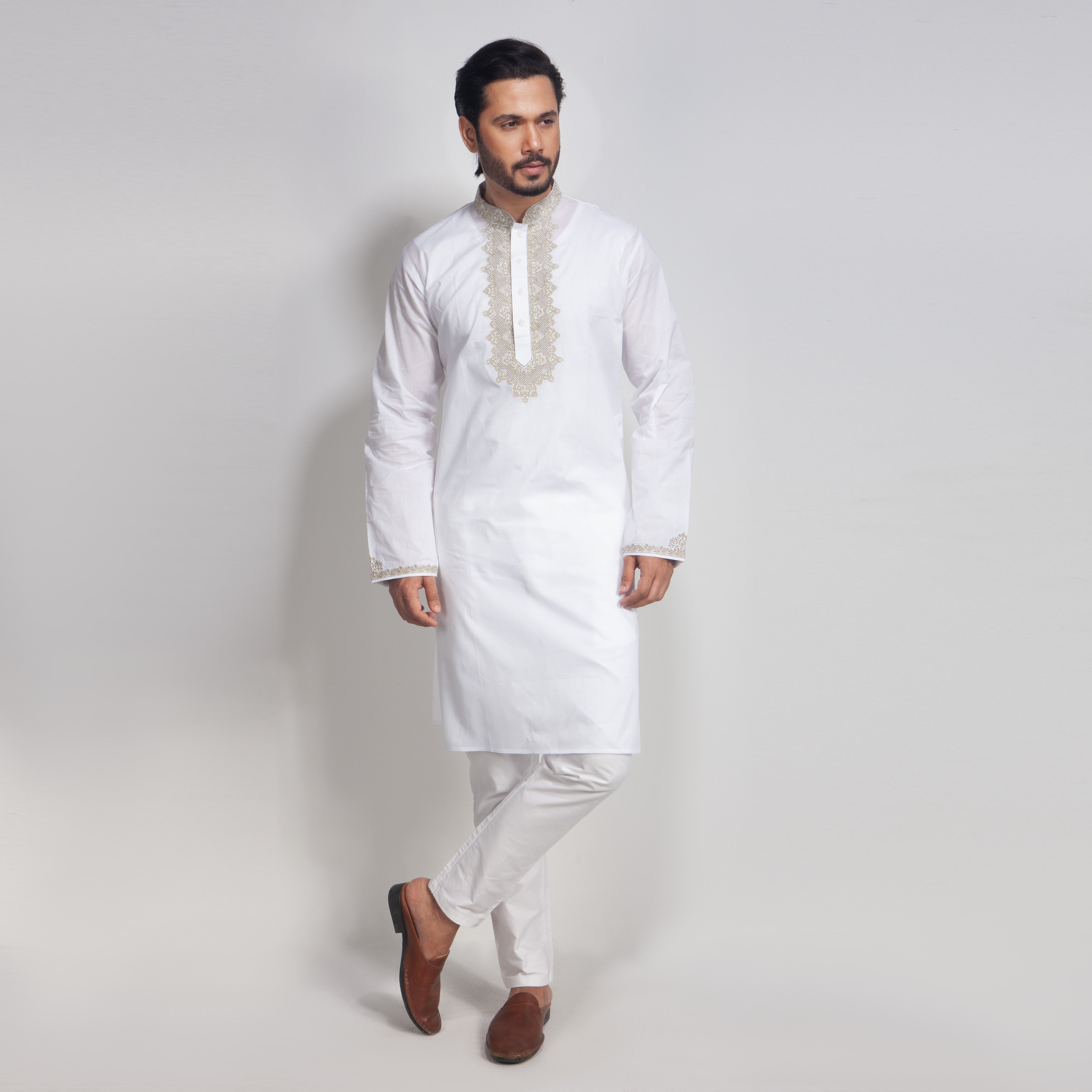 Man wearing a white kurta with embroidery on a plain background