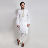 Man wearing a white kurta with embroidery on a plain background