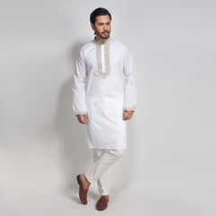 Man wearing a white kurta with embroidery on a plain background