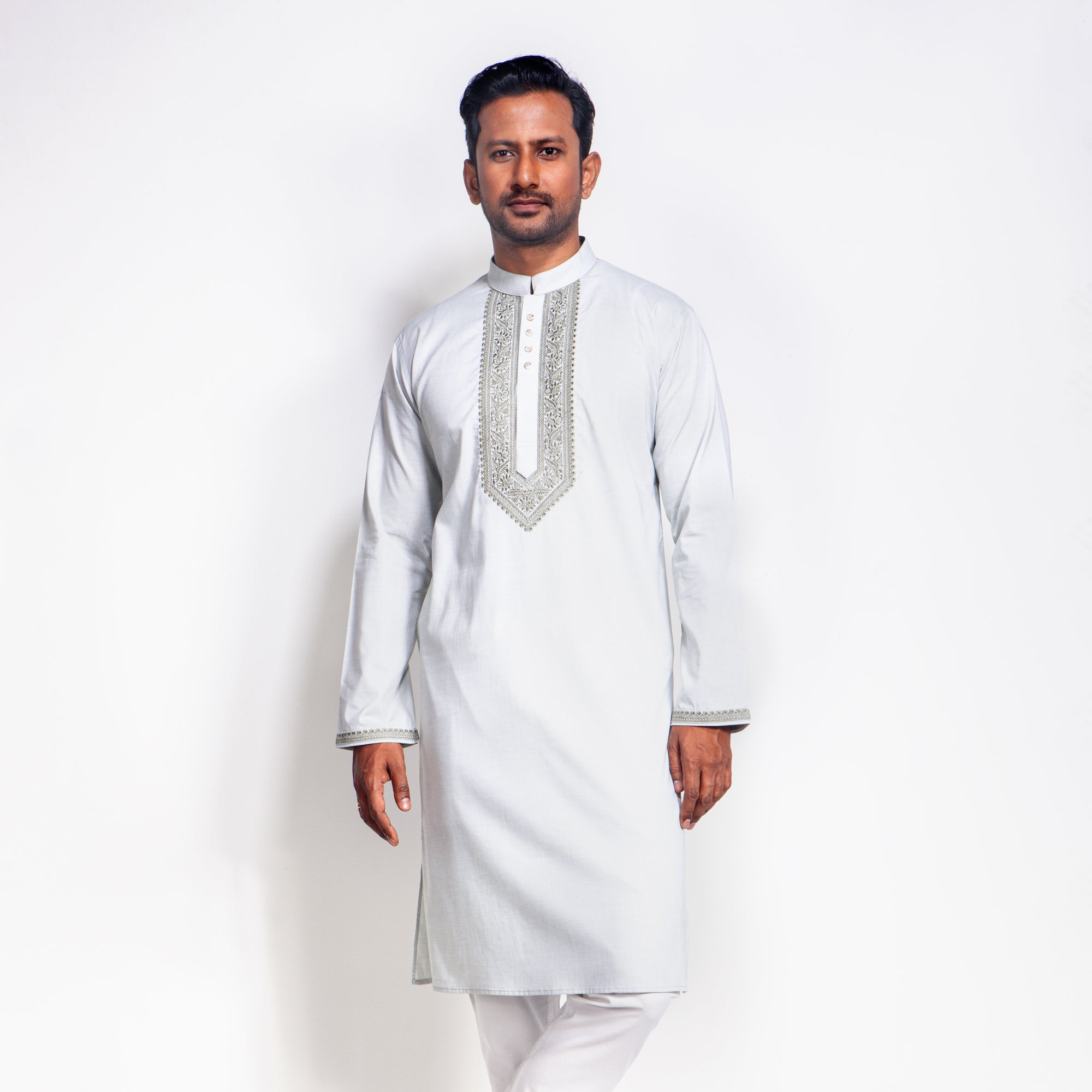 Man wearing a white embroidered panjabi against a white background