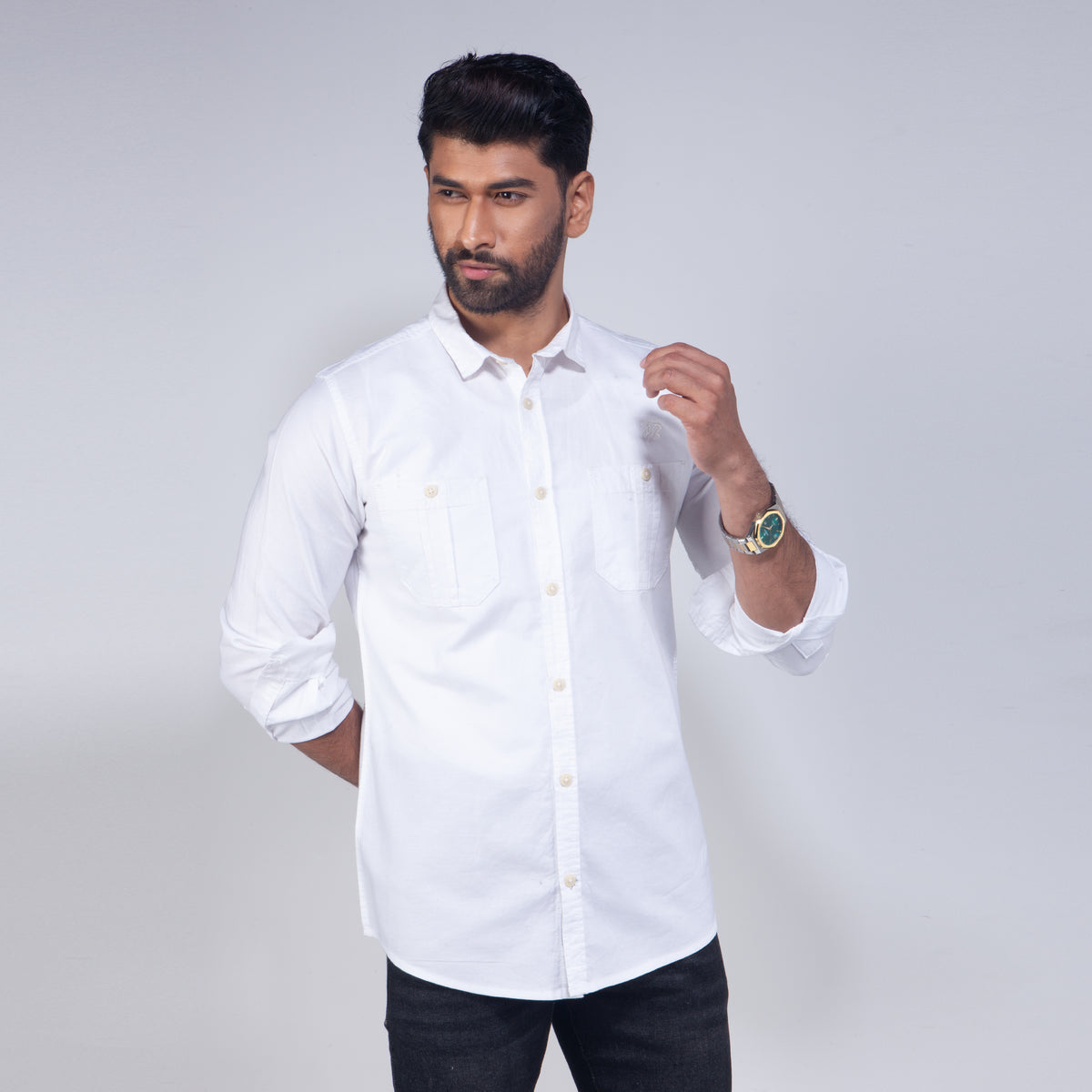 Man wearing a white shirt with rolled-up sleeves on a plain background