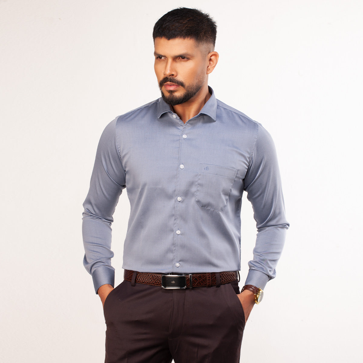 Man wearing a light blue formal shirt and dark pants on a white background