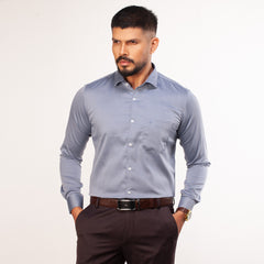 Man wearing a light blue formal shirt and dark pants on a white background