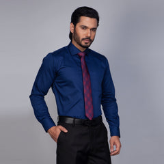Man wearing a blue dress shirt with a red tie against a gray background