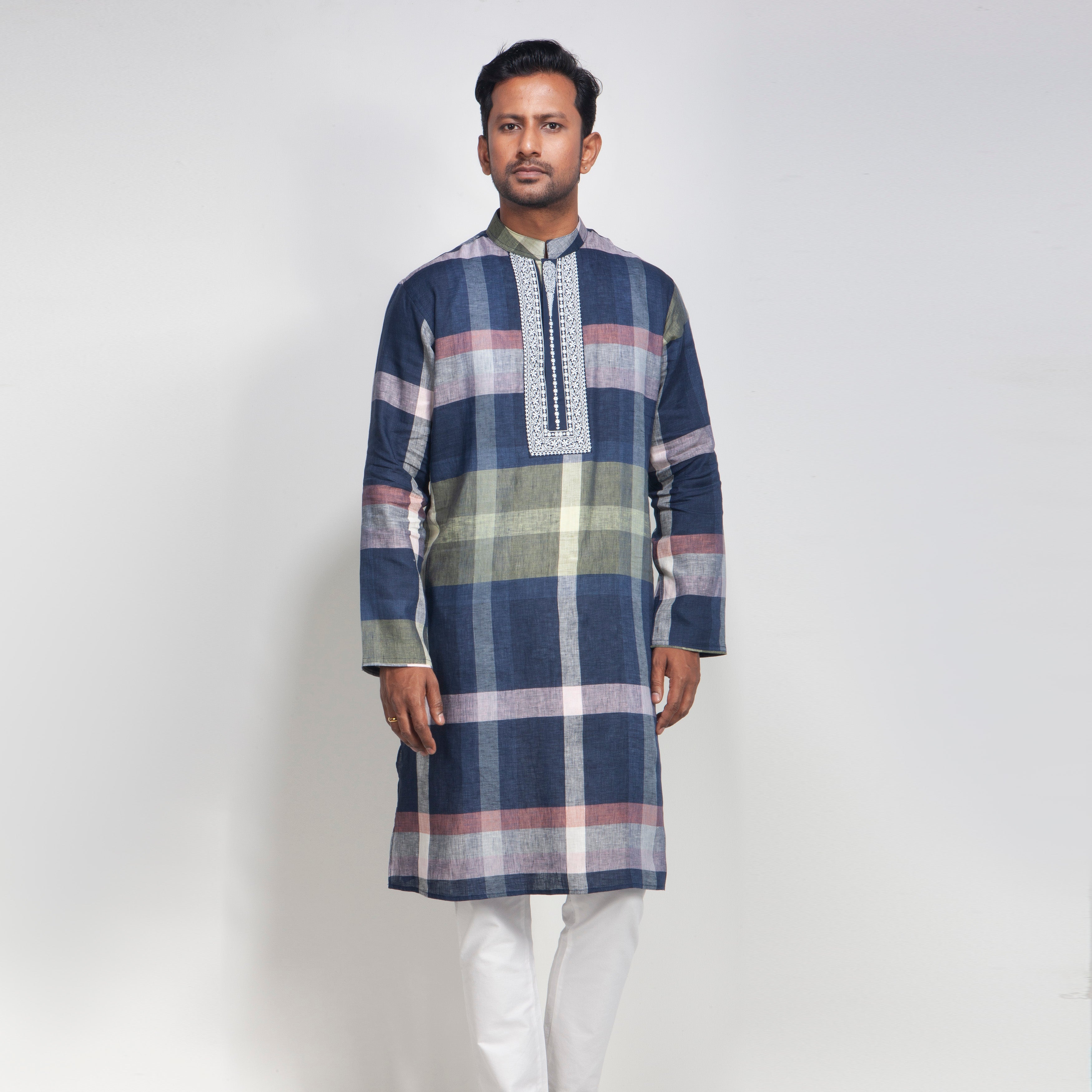 Man wearing a plaid panjabi with white pants on a light gray background