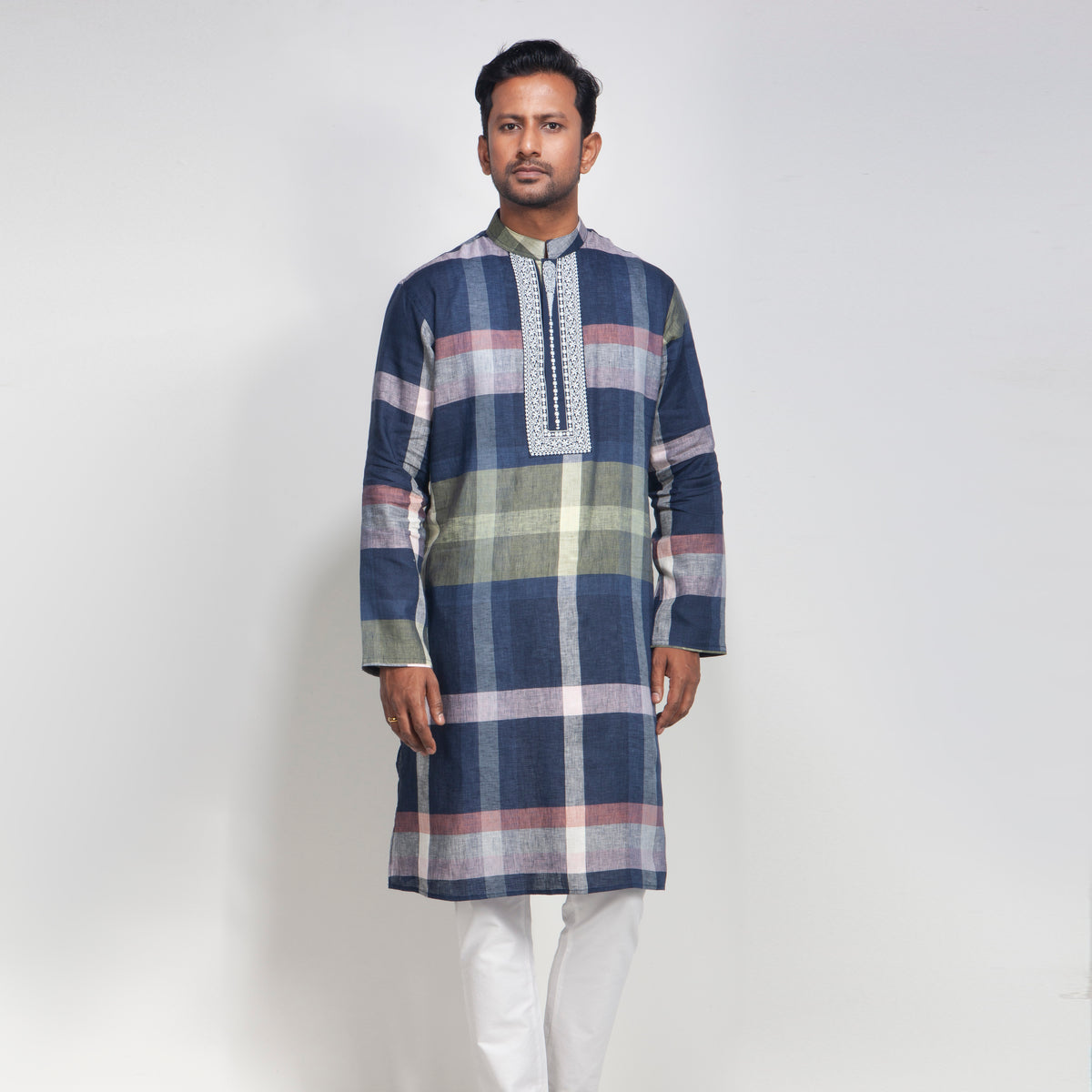 Man wearing a plaid panjabi with white pants on a light gray background