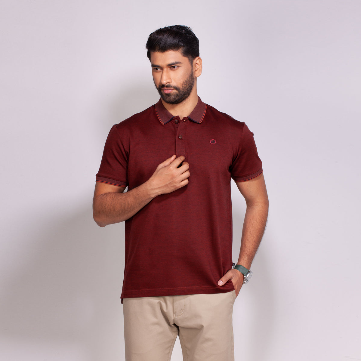 Man wearing a maroon polo shirt against a light gray background