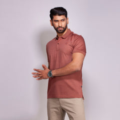 Man wearing a maroon polo shirt and beige pants against a light gray background