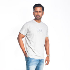 Man wearing a light gray t-shirt with a small logo on a white background
