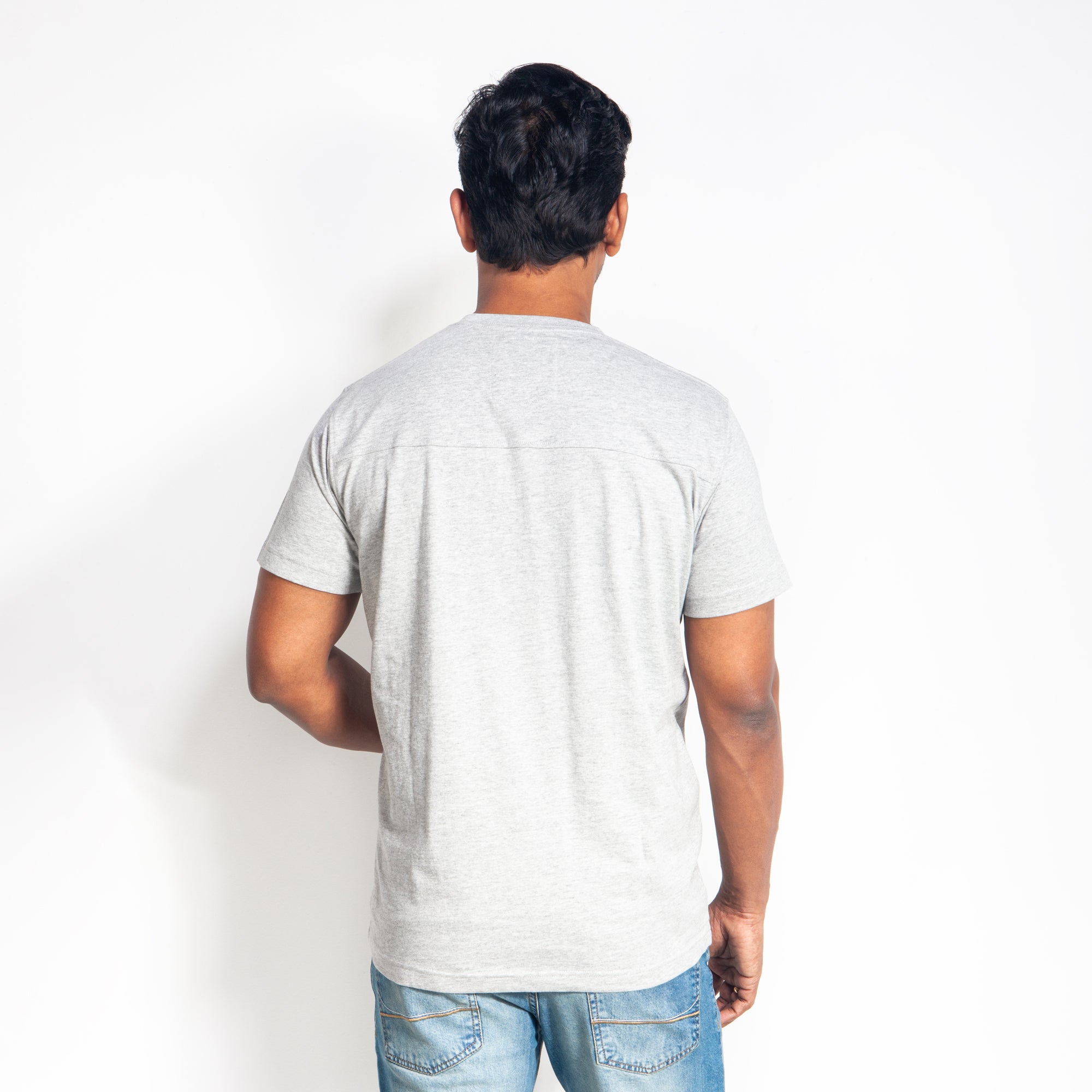 Man wearing a plain gray t-shirt against a white background