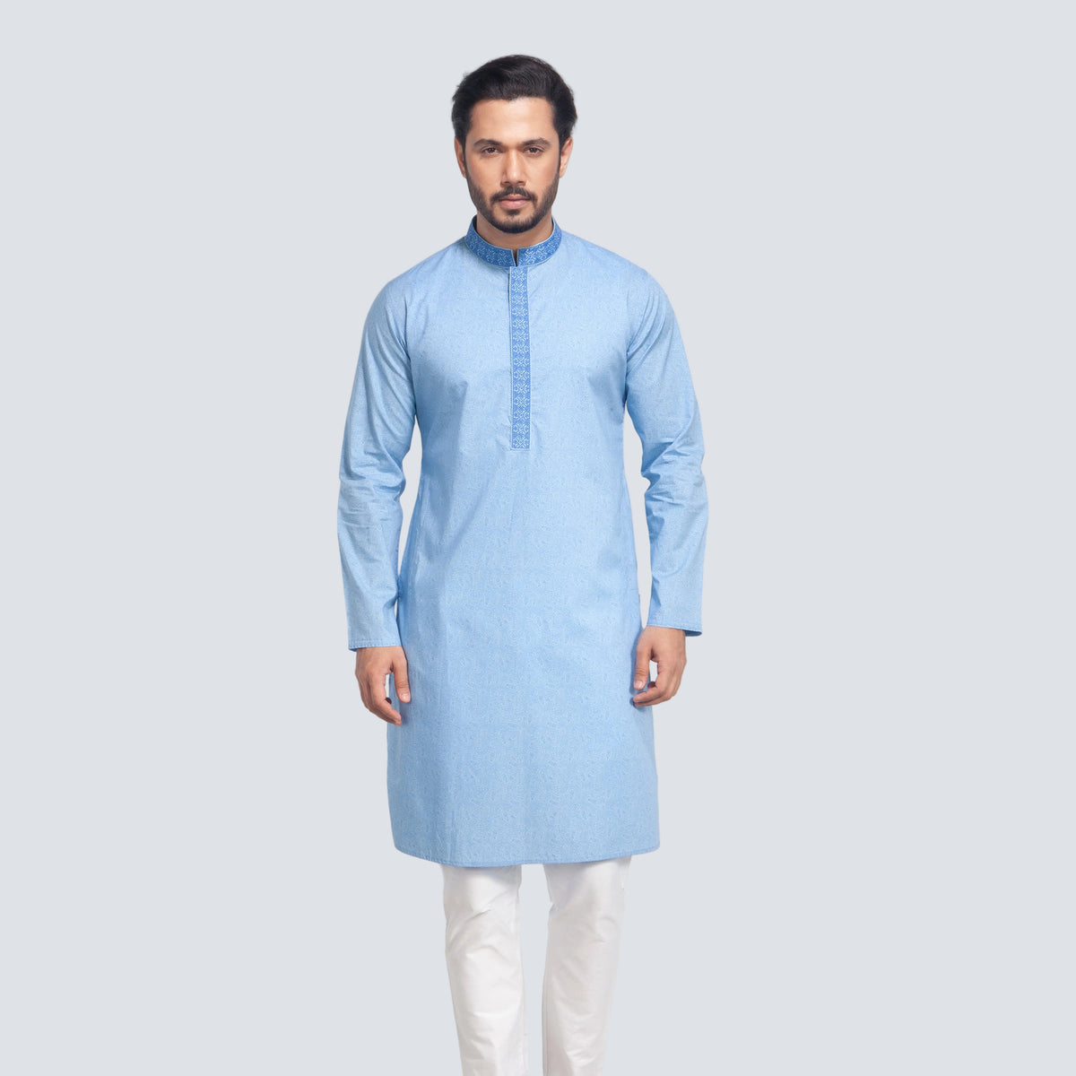 Man wearing a light blue panjabi with white pants on a plain background