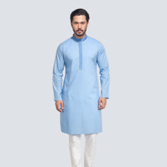 Man wearing a light blue panjabi with white pants on a plain background