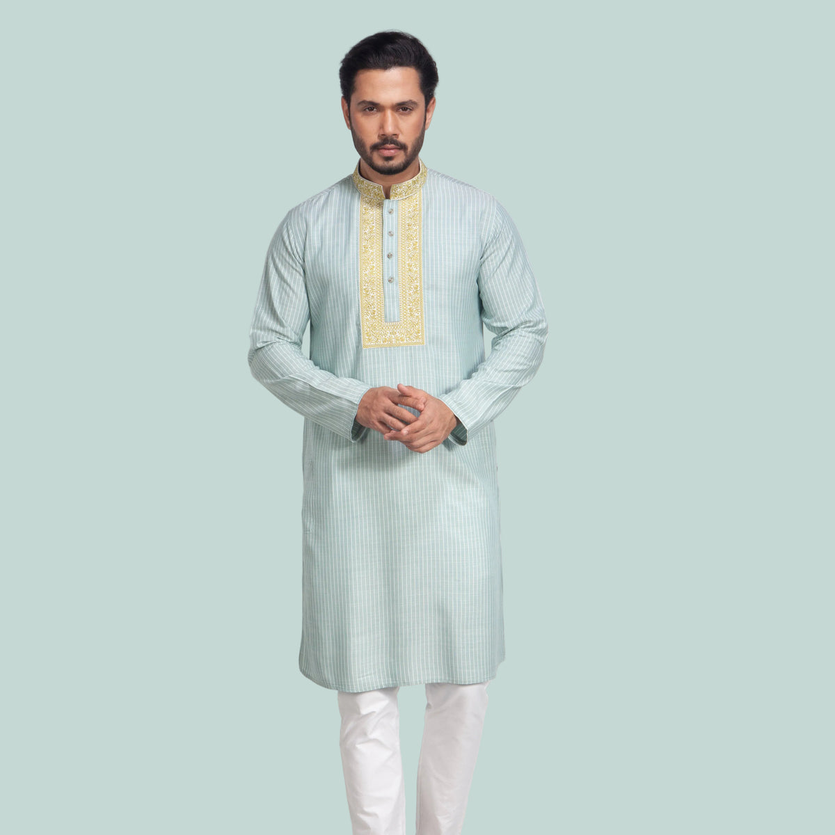 Man wearing a light green panjabi with white pants on a plain background
