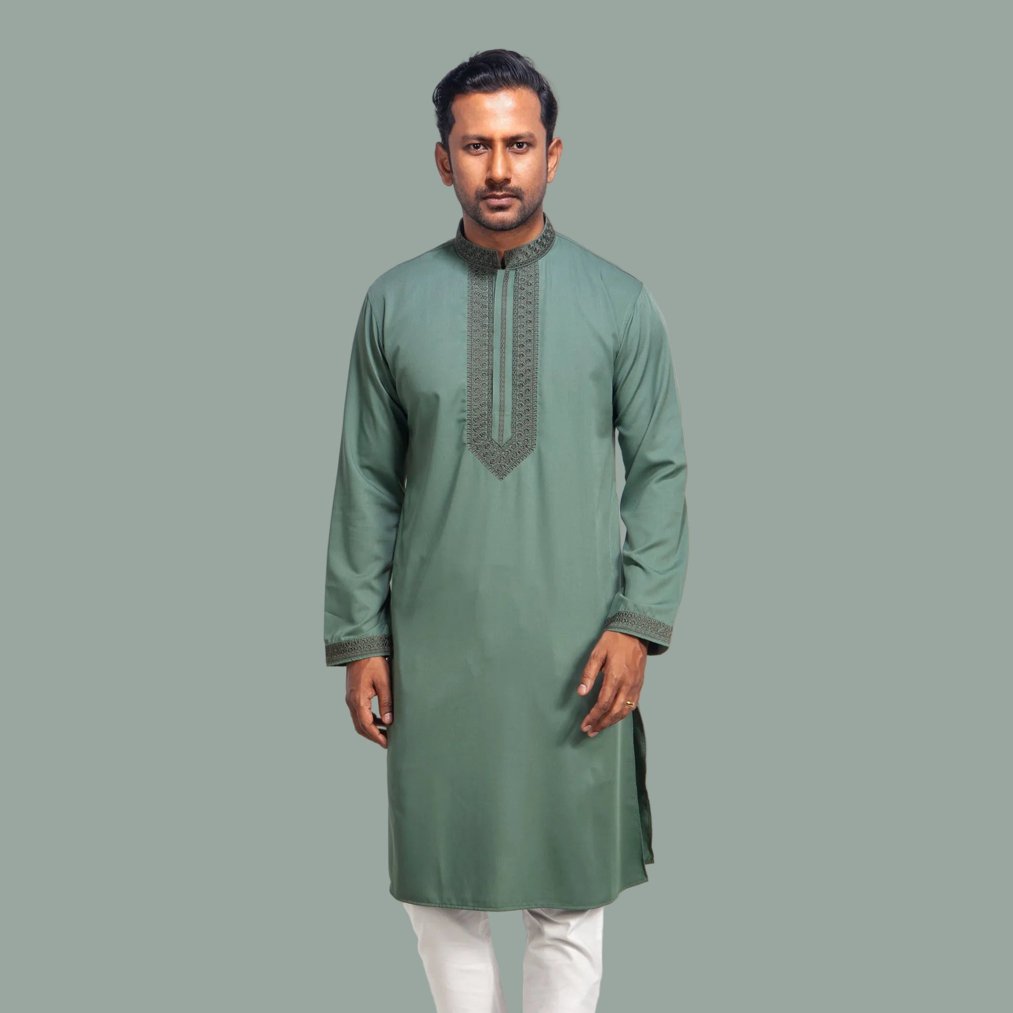 Man wearing a green panjabi with white pants on a light gray background