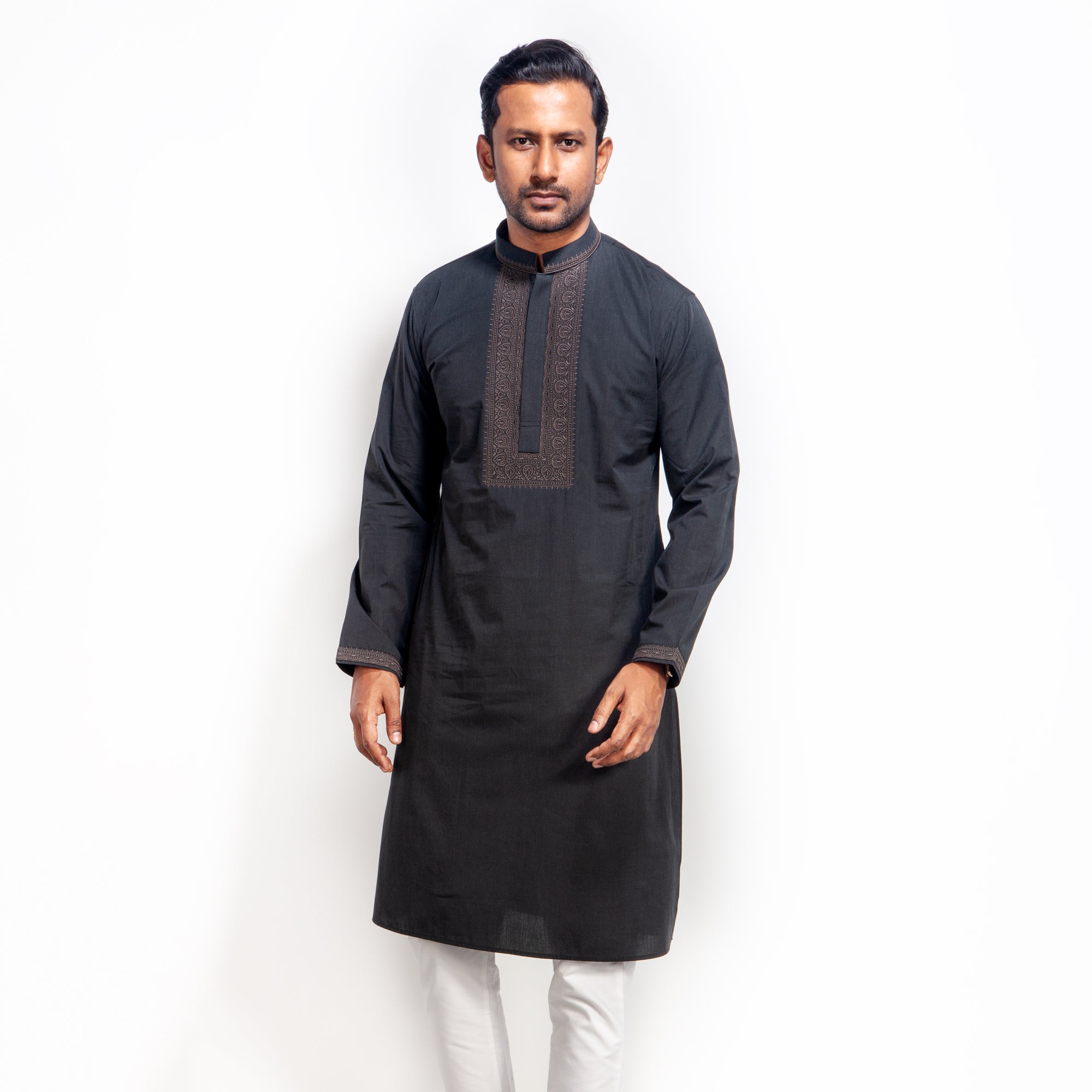 Man wearing a black kurta with white pants on a white background