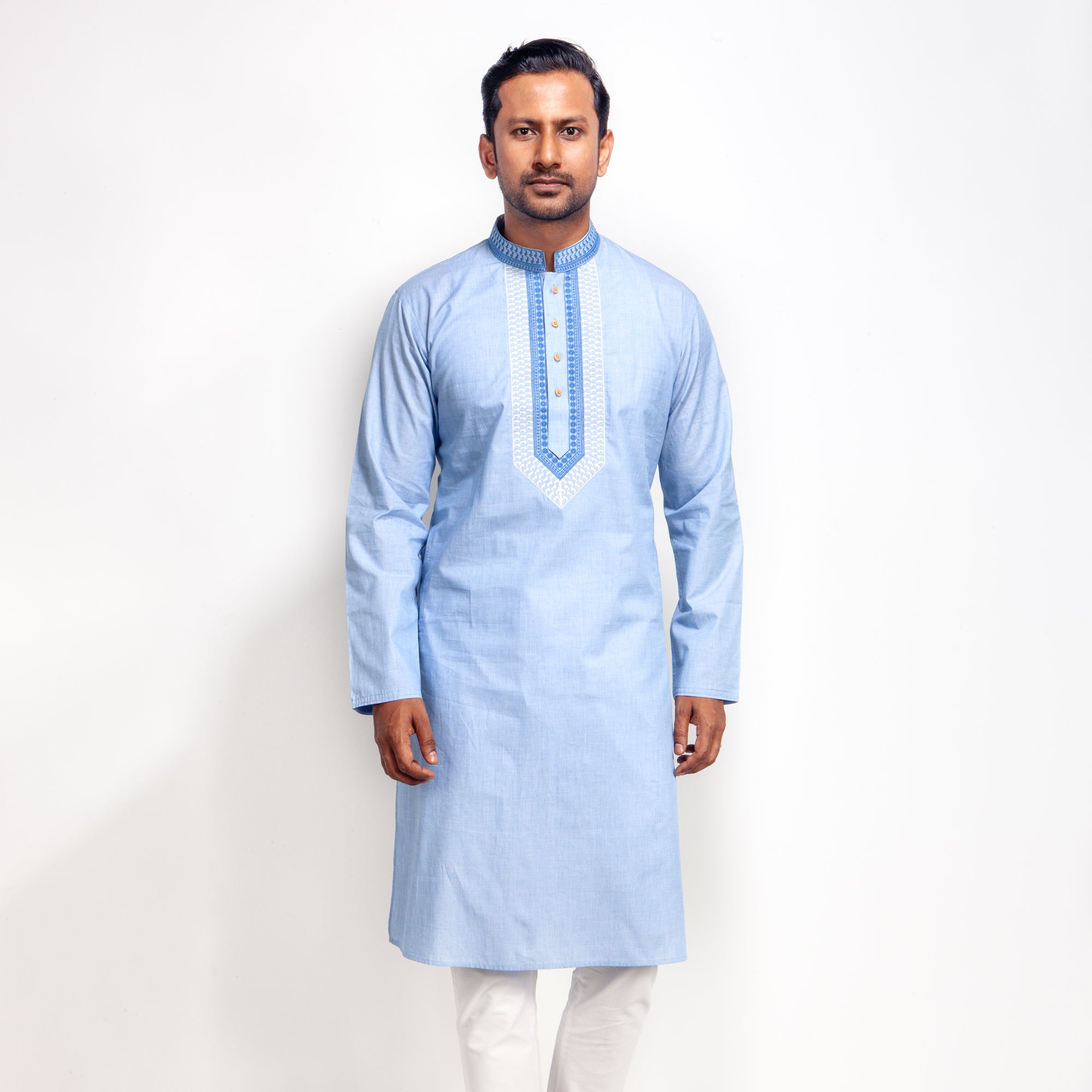 Man wearing a light blue kurta with white pants on a plain background