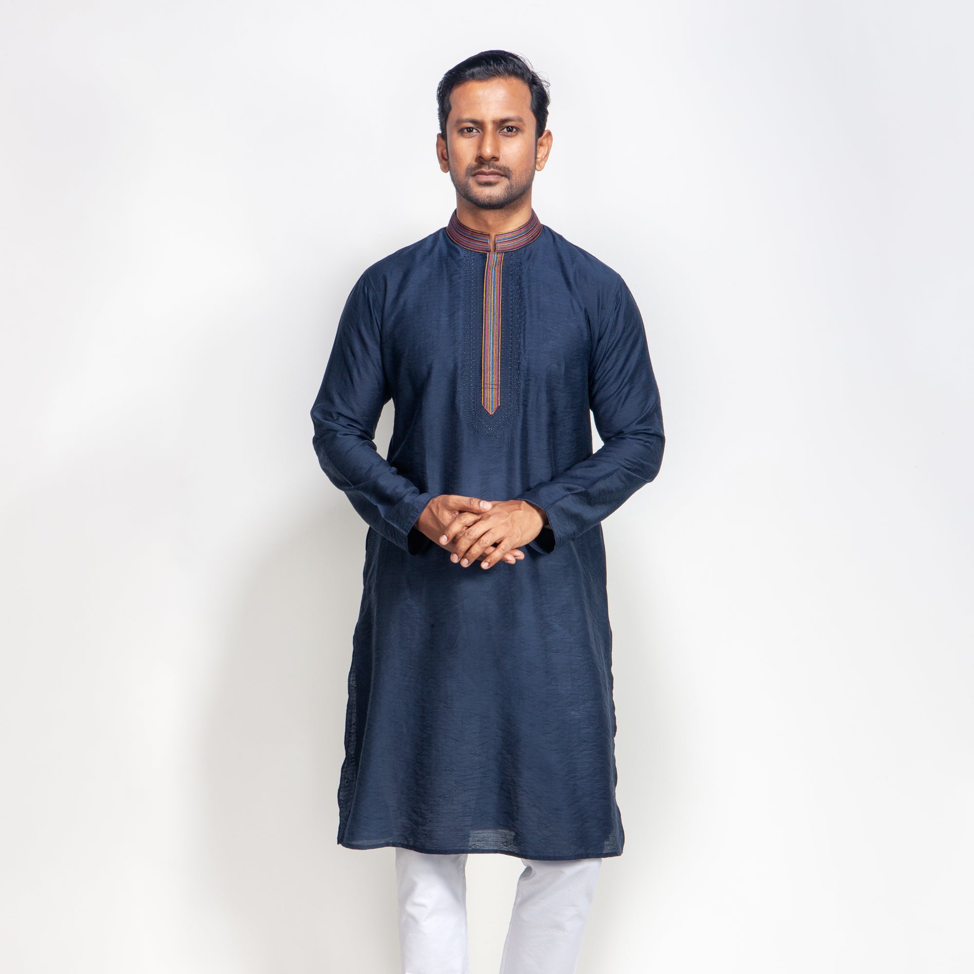Man wearing a navy blue kurta with white pants on a light gray background