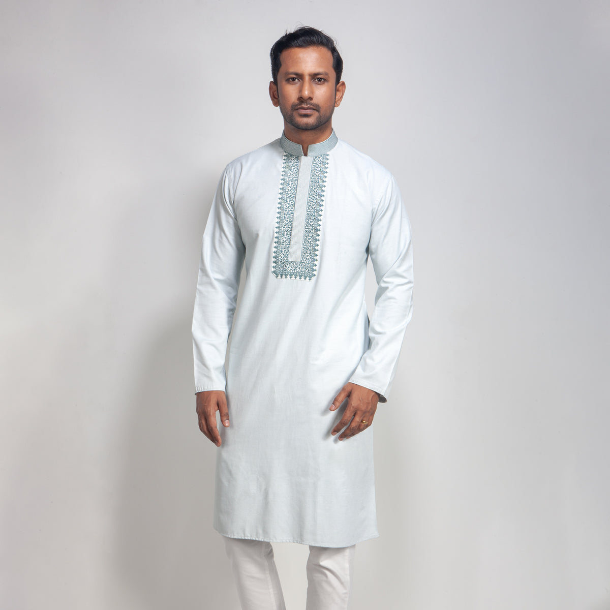 Man wearing a light gray kurta with intricate embroidery on a plain background