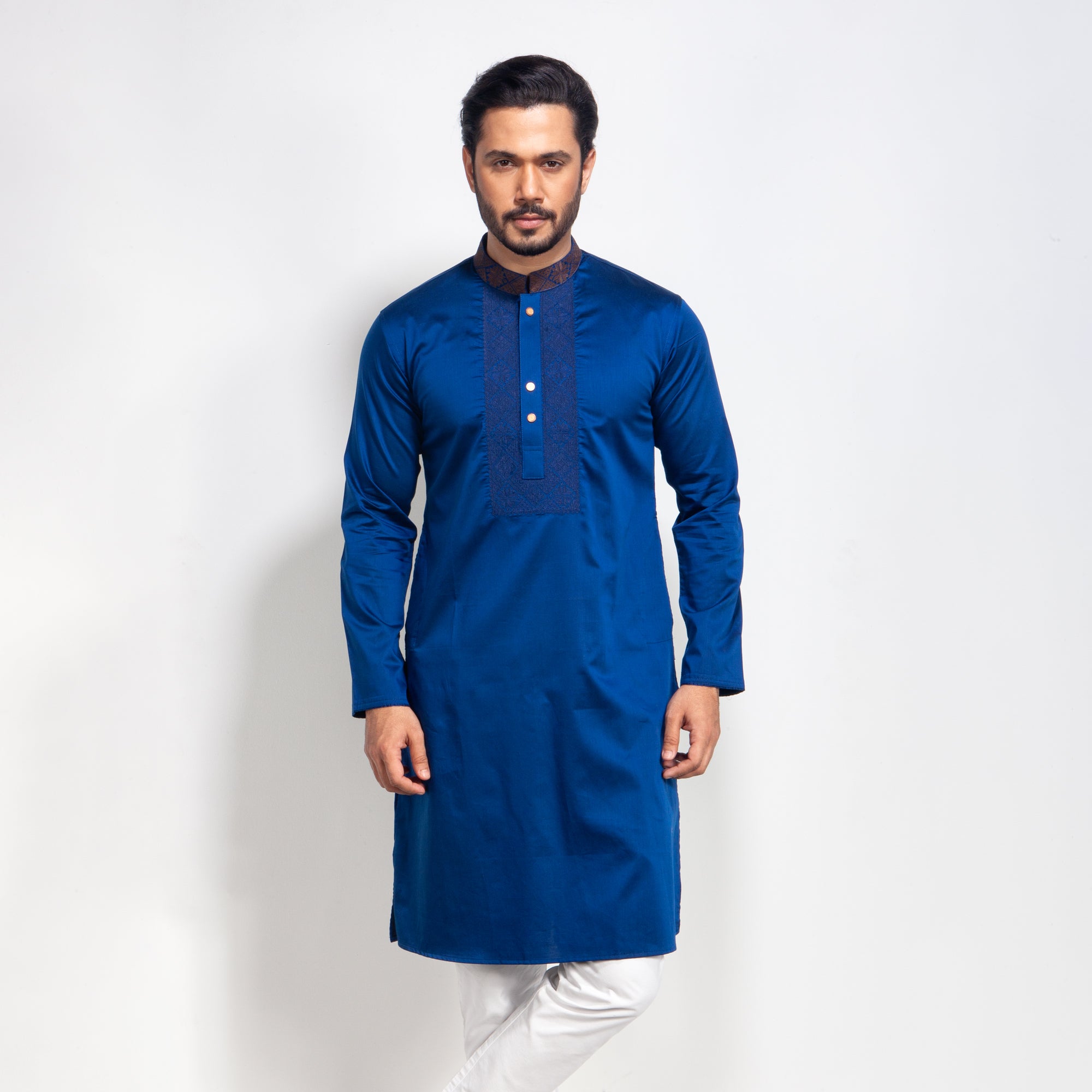 Man wearing a blue kurta with white pants on a light gray background