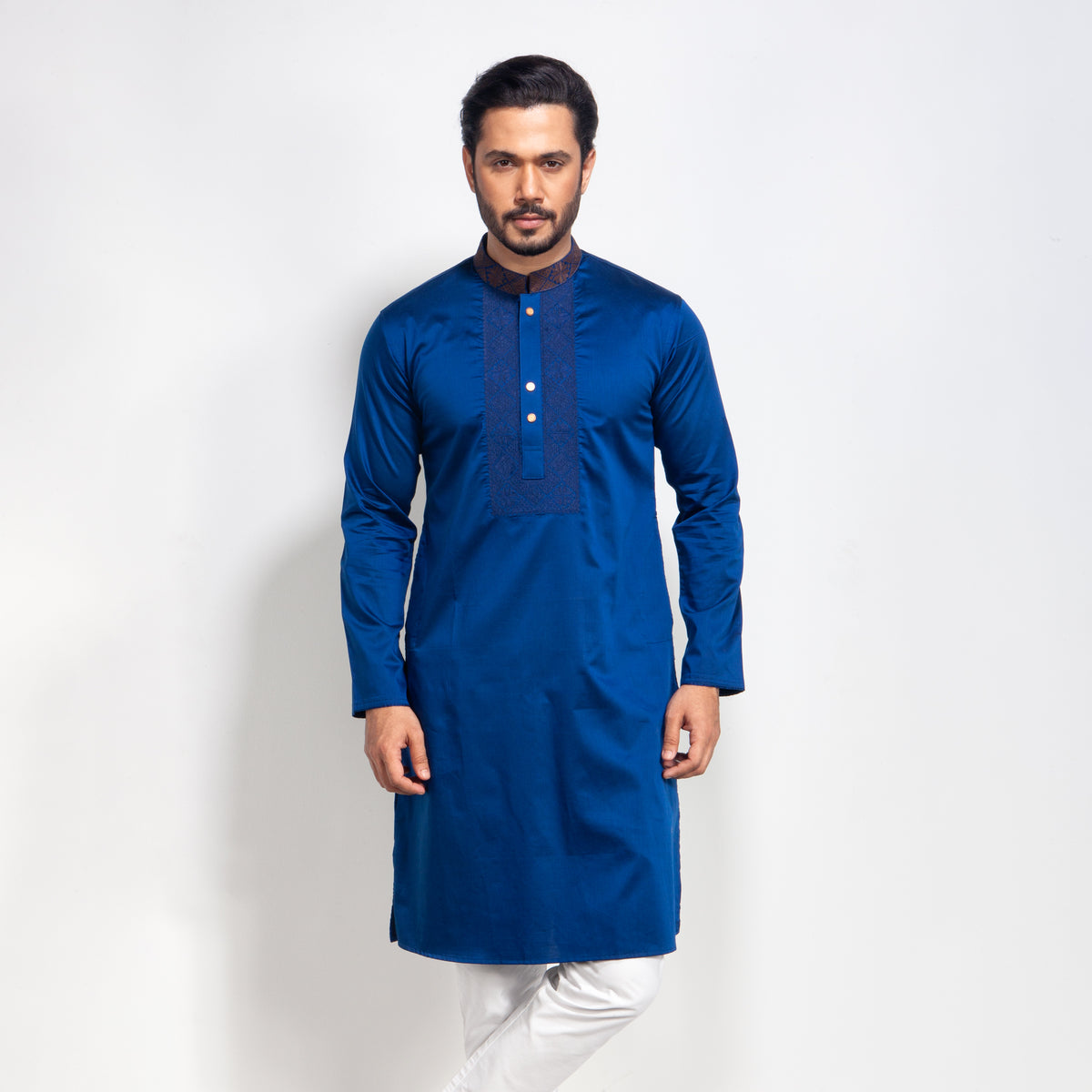 Man wearing a blue kurta with white pants on a light gray background