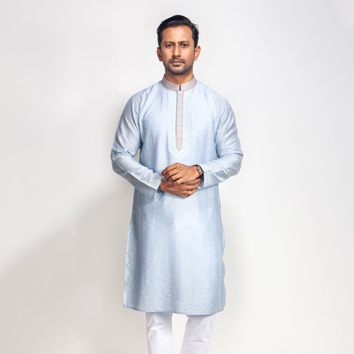 Man wearing a light blue kurta with white pants on a plain background