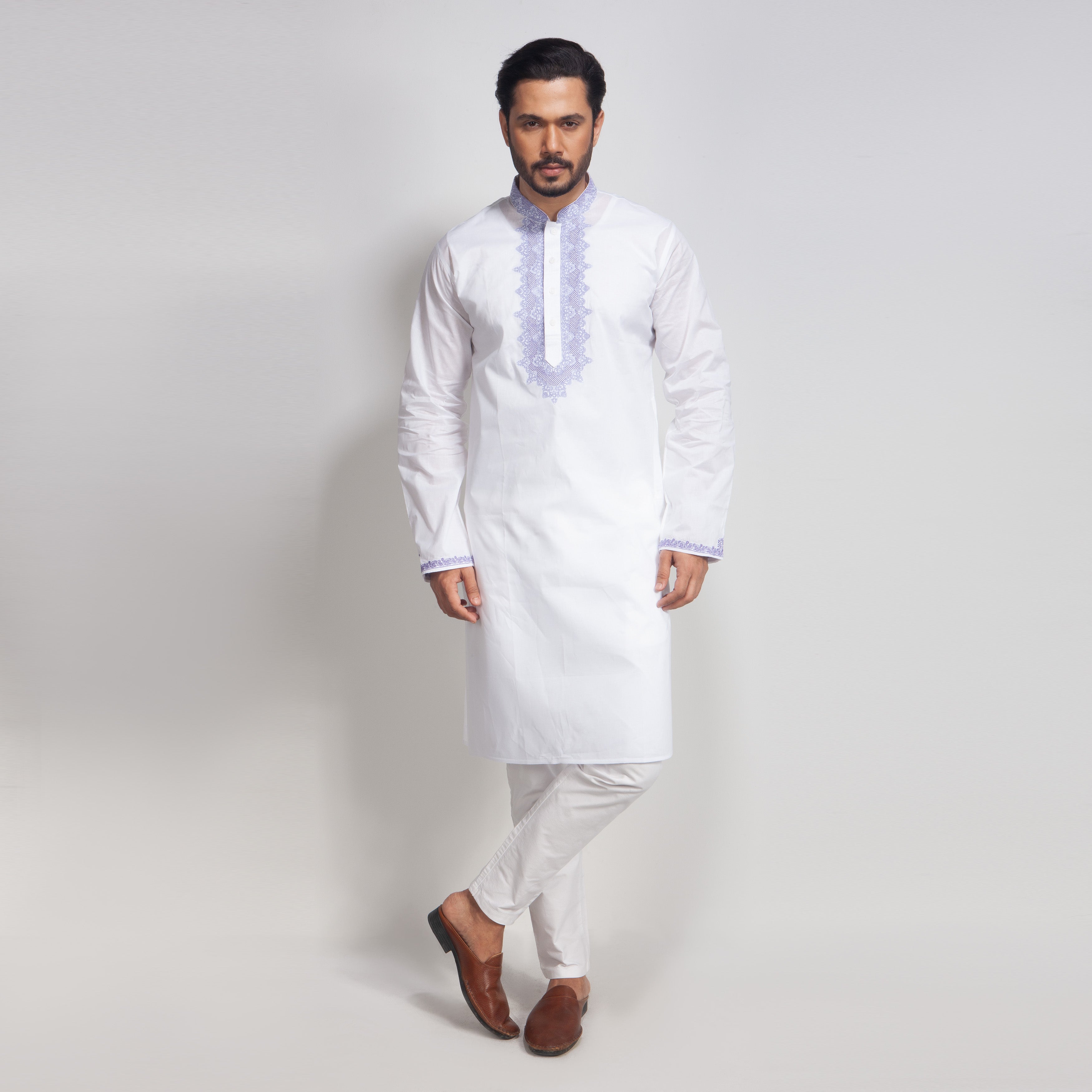 Man wearing a white kurta with embroidery on a light gray background
