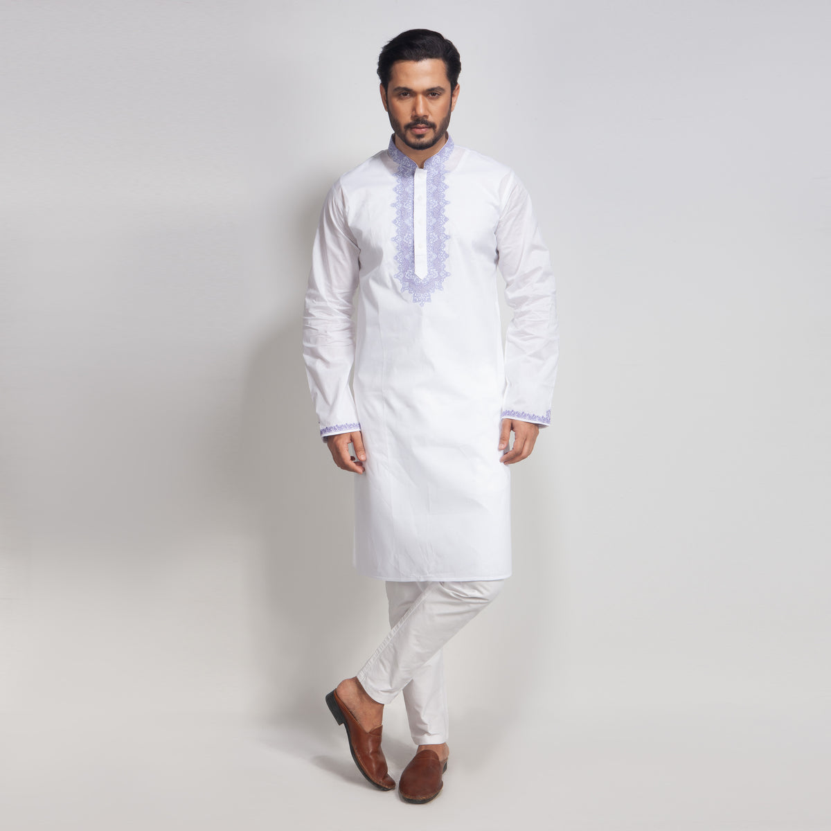 Man wearing a white kurta with embroidery on a light gray background