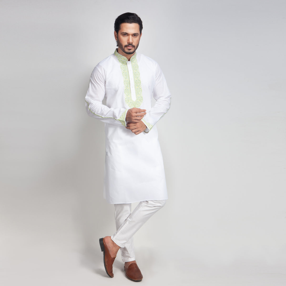 Man wearing a white kurta with a light green scarf on a plain background