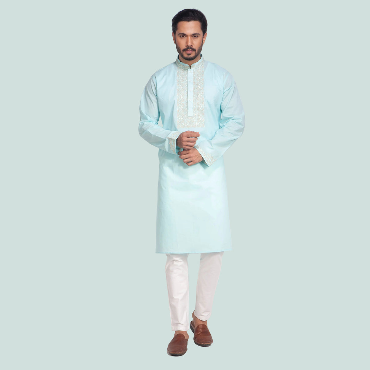 Man wearing a light blue kurta with white pants on a white background